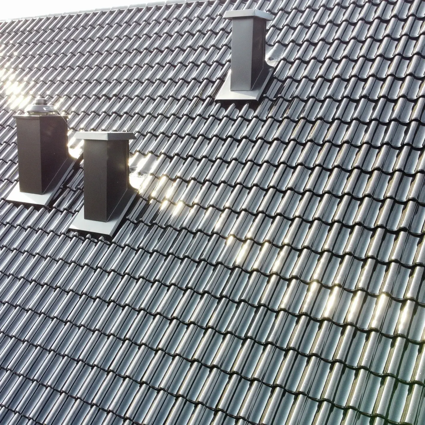 Nylagt svart betongtak med två måttanpassade ventilationshuvar i lackad plåt