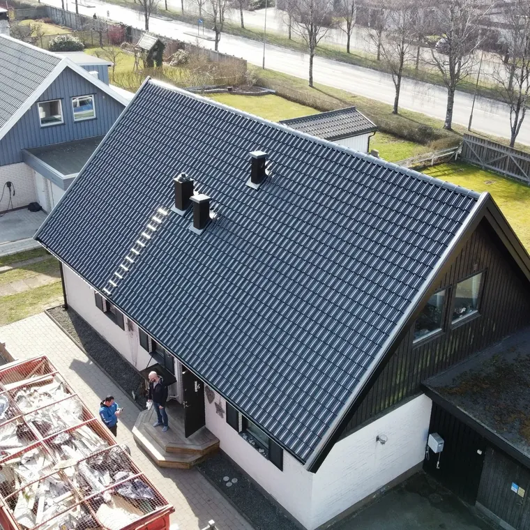 Villa med nylagt svart tak, takstege och ventilationshuvar