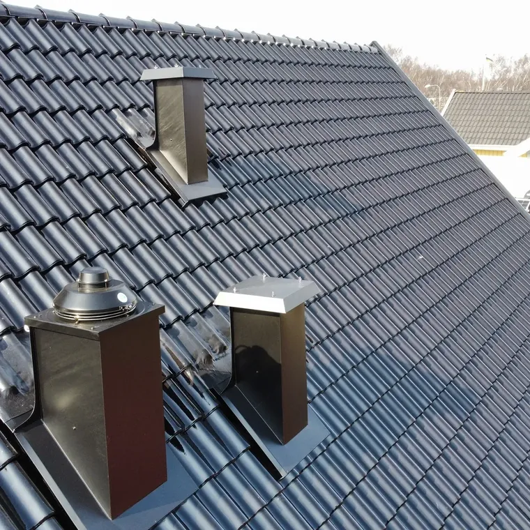 Svart betongtak med egentillverkade ventilationshuvar i aluminium