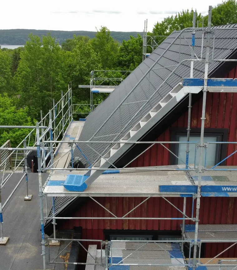 Röd villa med ställning och nylagt mörkt tak i skogsmiljö
