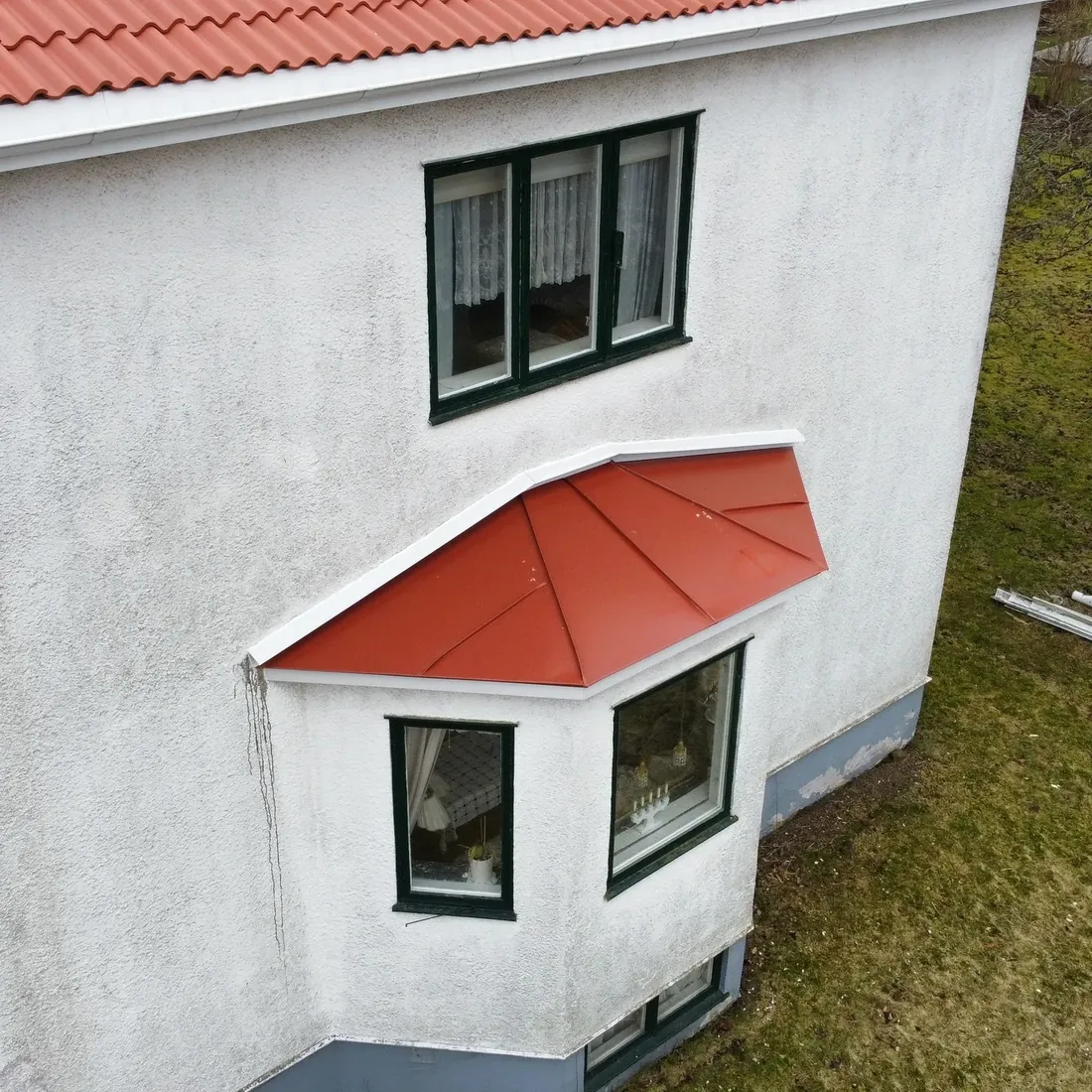 Vit villa med burspråk klätt i rödlackerad plåt